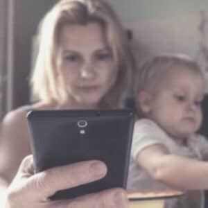 Mother using phone with her children on her lap.