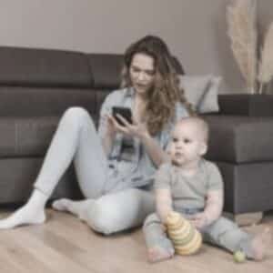 Mother on phone with toddler near by Single Mama Way