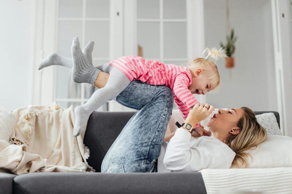 Single mum laughing and playing with her child at home.