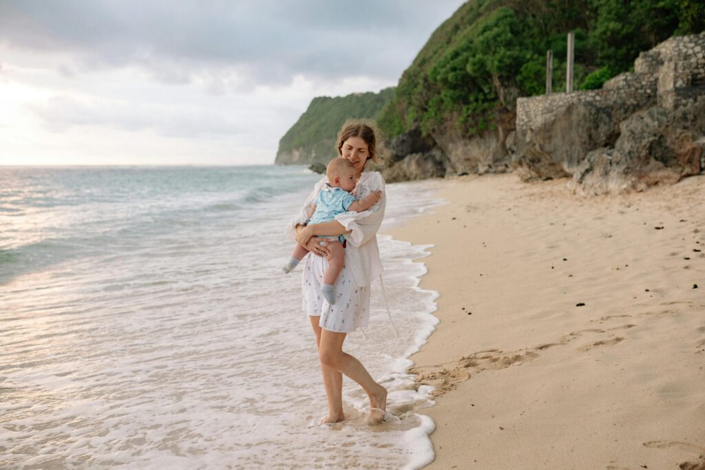 Single mum walking on the beach with her baby, finding calm moments that rebuild trust in yourself.