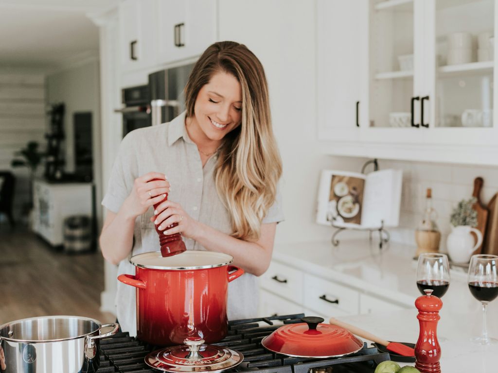 confidence after divorce 1 - Single Mama Way Counselling Smiling woman cooking a meal as an act of self-care and confidence after divorce.