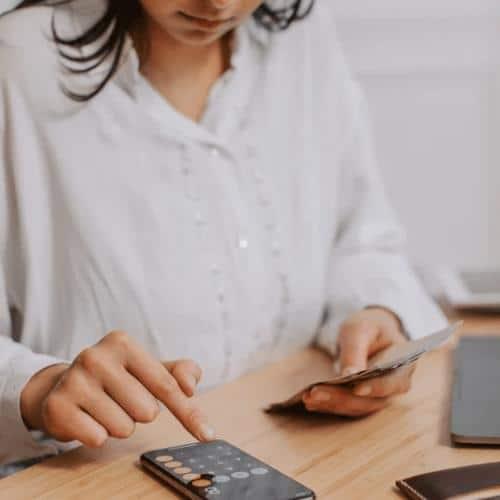 Woman calculating on phone with money in her hands