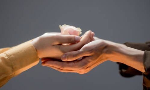 Charity Support Single Mama Way Female hands holding another female's hands holding a flower.