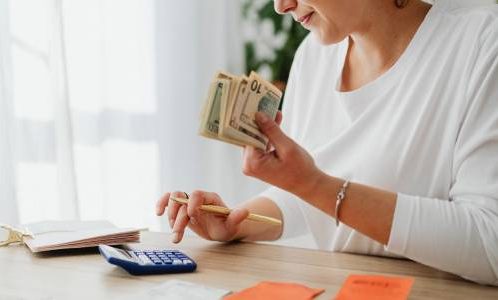 Woman calculating on calculator holding paper money Money matters often dominate our every waking moment.